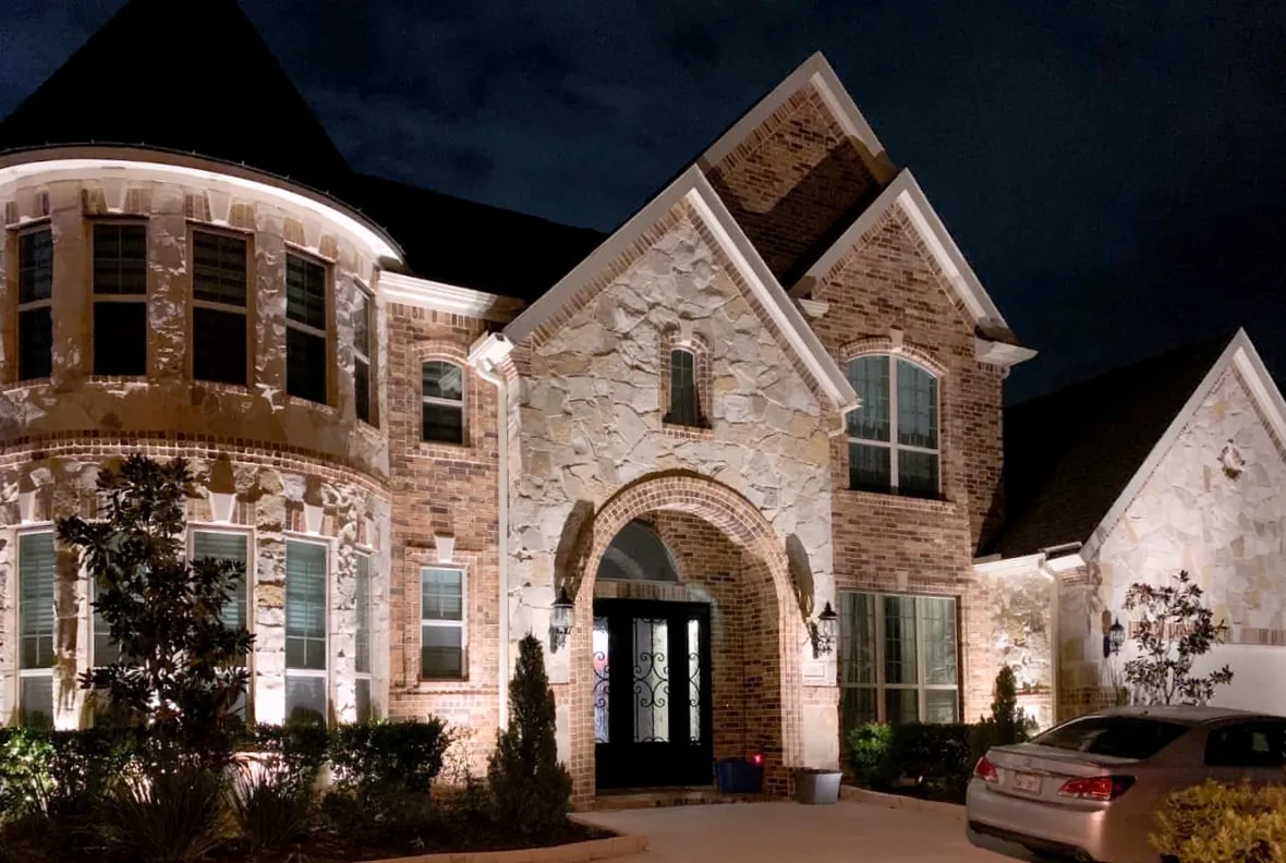 hl-home-design-stone-facade-1180.webp Stone facade and gabled roofline picked out by warm accent lighting after dark