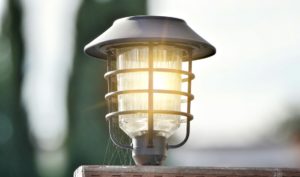 An old, dusty halogen lighting fixture on a fence is updated with an outdoor LED lighting fixture
