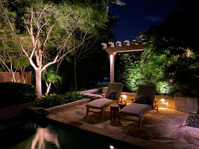 Two pool chairs sit under a pergola at night in a family's outdoor haven