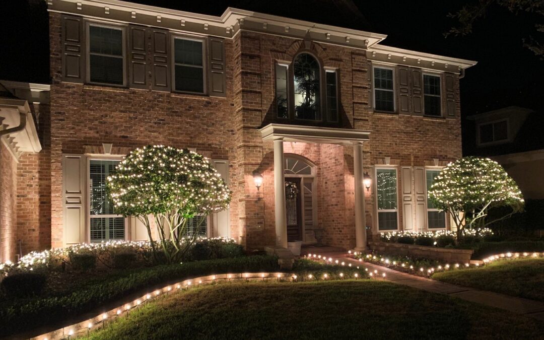 Brick house with winter lights lining the driveway and decorating the trees in front of the house