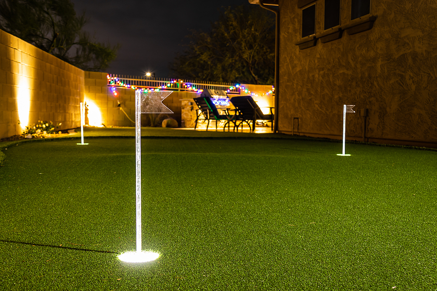 Nighttime image of a personal home putting green with illuminated holes. Backyard lighting