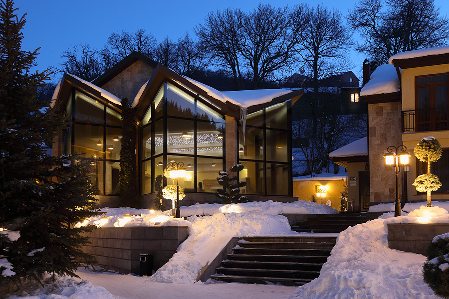 Cottages with glass walls in snow at winter evening, lighting lanterns
