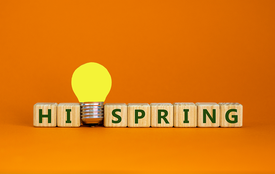 Hi spring symbol. Wooden cubes with words 'hi spring'. Yellow light bulb. Beautiful orange background. Business and hi spring concept. Copy space.