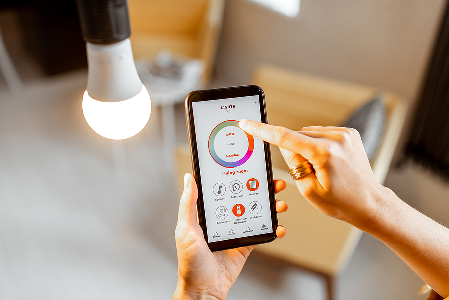 Controlling light bulb temperature and intensity with a smartphone application. Concept of a smart home and managing light with mobile devices. Energy bill.