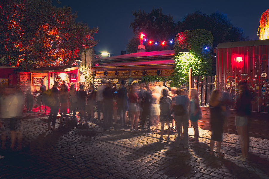 An outdoor club illuminated by vibrant lights, creating an inviting atmosphere that attracts customers and enhances the nightlife scene.