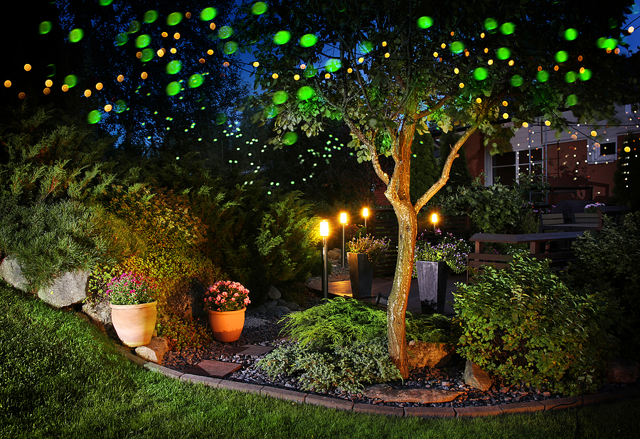 Outdoor party lights illuminating a cozy garden patio in the evening, creating a festive and inviting atmosphere.
