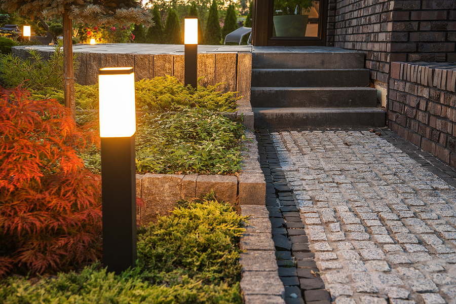 Modern LED light posts lining a garden path in a backyard, highlighting landscape features with warm, inviting outdoor lighting.