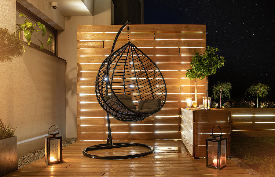 Tranquil backyard garden at night with cozy furniture and soft lighting under a starry sky.